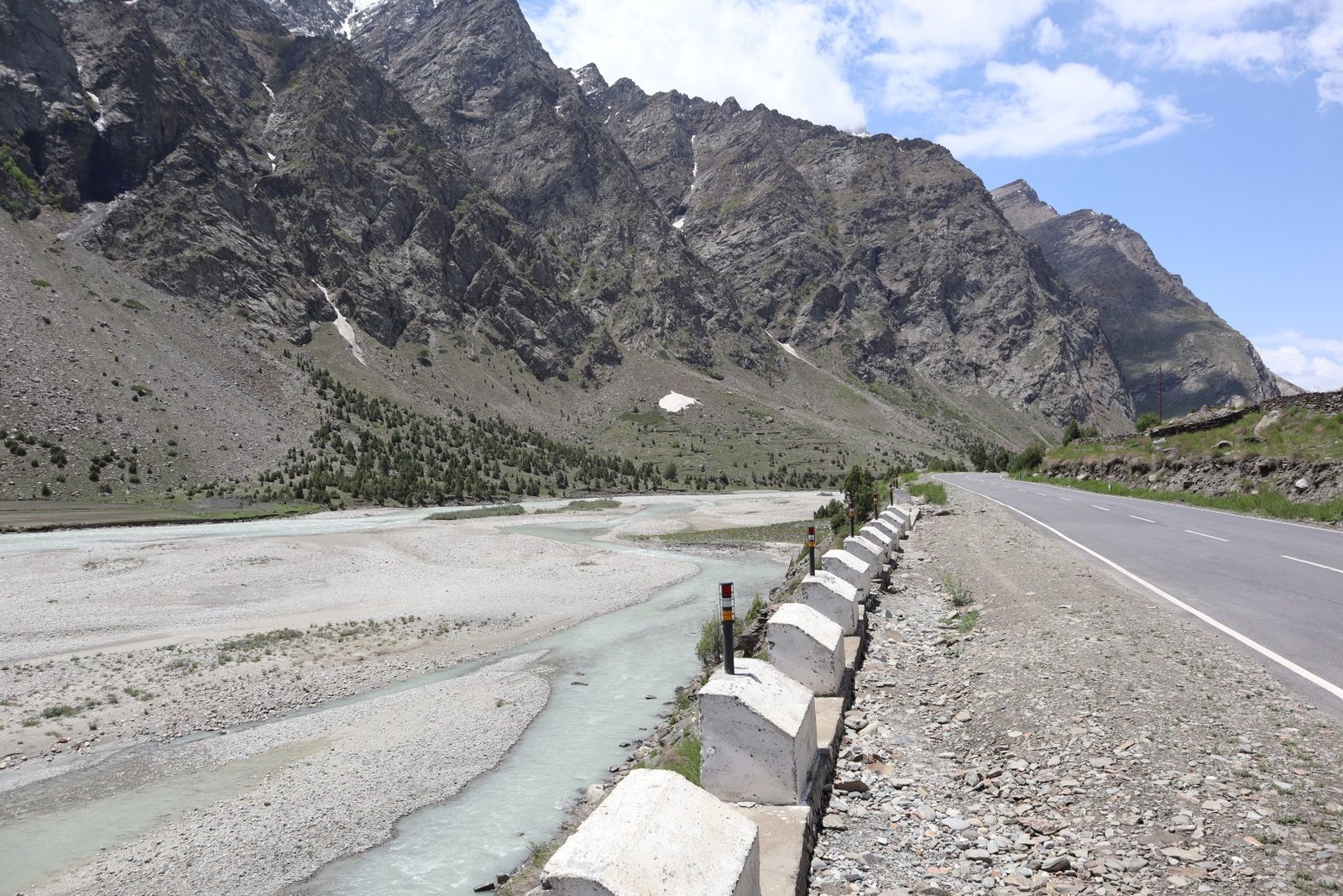Leh Ladakh bike trip along a mountain road beside a river in remote terrain